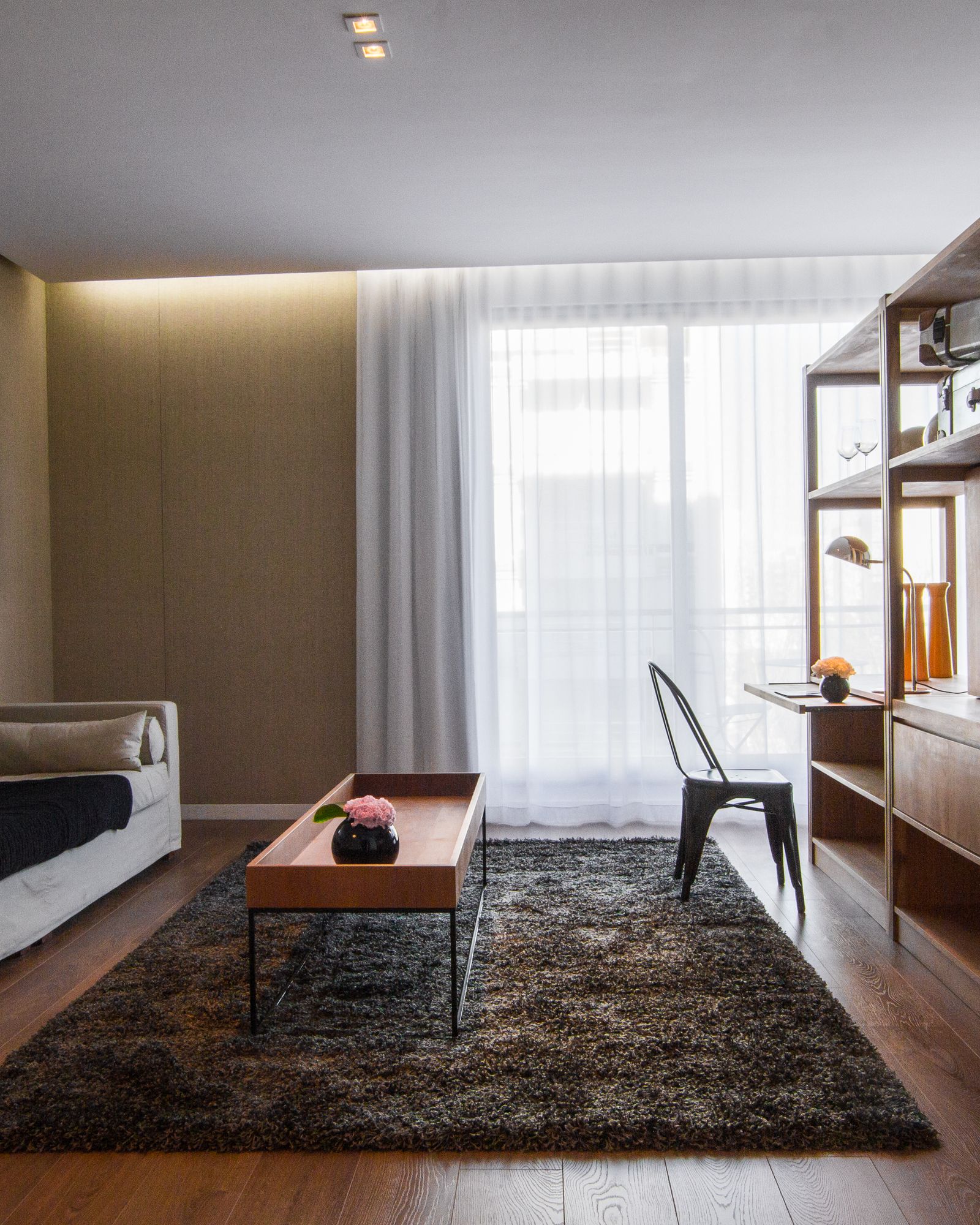 Área común de hotel con revestimientos de madera, mobiliario a medida y piso continuo.